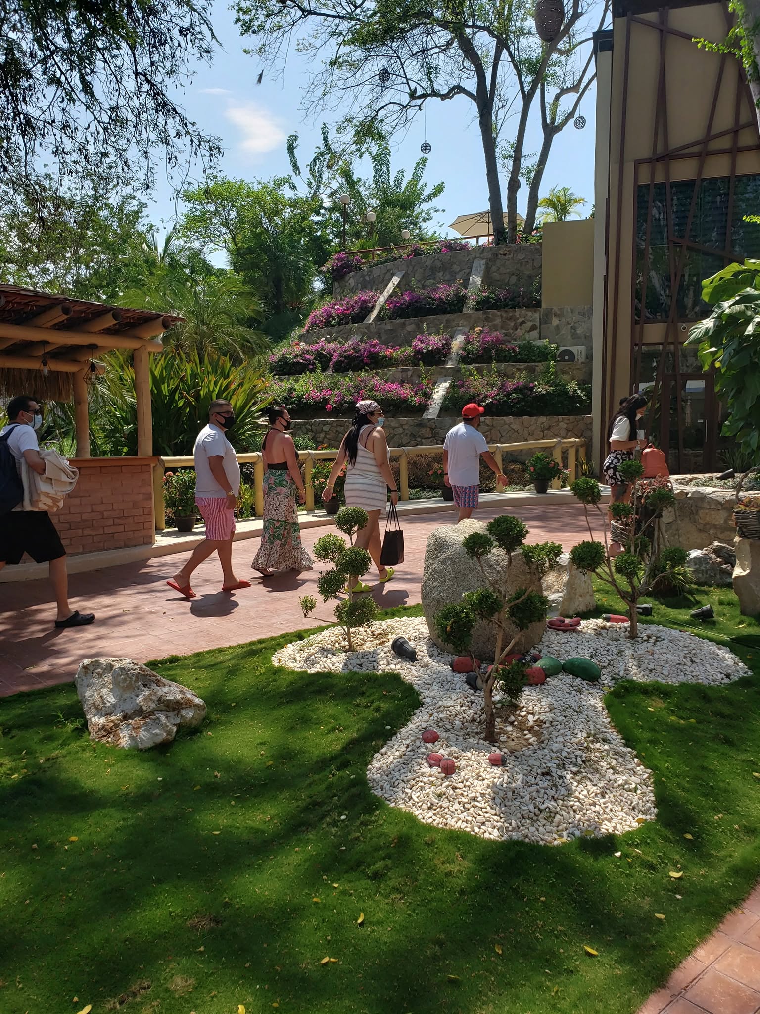 Visitantes recorriendo un jardín diseñado por El Edén, con cascada de buganvilias y topiarios